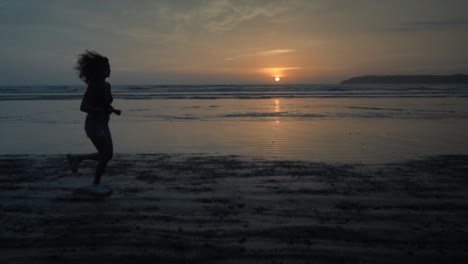 Landschaftsansicht-In-Zeitlupe-Einer-Silhouette-Einer-Jungen-Frau,-Die-Bei-Sonnenaufgang-An-Einem-Sandstrand-Am-Meer-Läuft