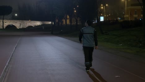 Tracking-shot-of-athletic-person-walking-on-track-At-night-time-near-aqueducts