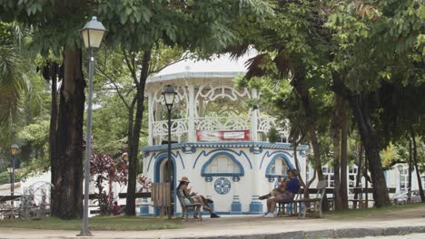 People-on-park-benches-by-a-bandstand-in-a-city-park
