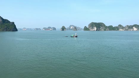 Small-boat-passing-through-in-open-Halong-Bay-scene,-Vietnam