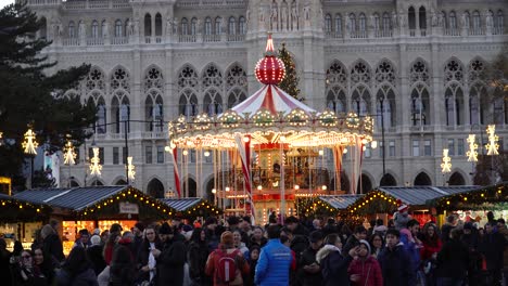 Blick-Auf-Das-Karussell,-Während-Sich-Menschen-Auf-Dem-Weihnachtsdorfmarkt-Gegenüber-Dem-Rathaus-In-Wien,-österreich,-Versammeln