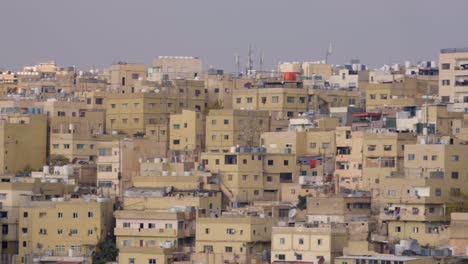Flock-of-pigeons-flying-over-densely-packed-houses-and-cityscape-view-in-the-capital-city-of-Amman-in-Jordan