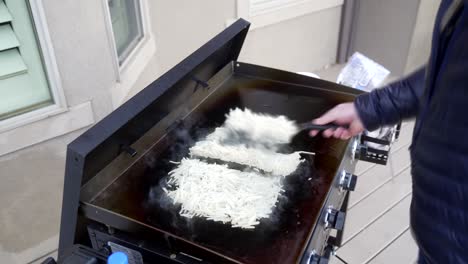Time-lapse-of-a-man-making-hash-brown-egg-omelets-on-a-flat-top-griddle
