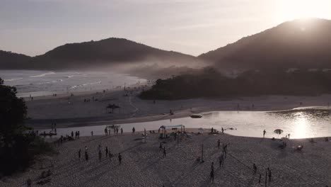 Drone-moving-backwards-at-a-beatifful-beach-with-a-lot-of-action-of-people-in-the-sand