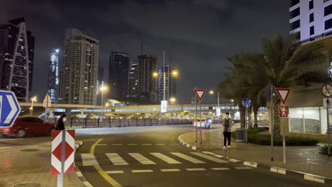 People-crossing-the-street-in-front-of-a-Taxi-seen-in-intersection-near-the-train-station-in-Dubai-at-night