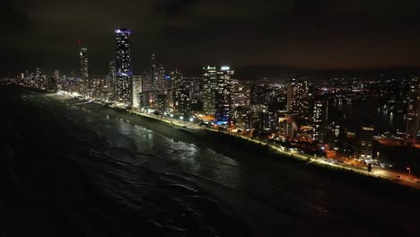 Totally-breathtaking-views,-drone-flying-high-out-at-sea-capturing-Surfers-Paradise-nightscape-of-glistening-water-and-sparkling-highrise-lights