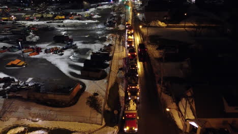 dump-trucks-loaded-with-tons-of-Snow-Cleared-from-Buffalo-Streets-and-sidewalks-After-severe-Winter-snowstorm,-night-aerial-dolly-in-shot