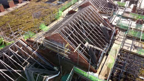 Unfinished-timber-rooftop-scaffolding-framework-on-townhouse-property-development-site,-Aerial-view