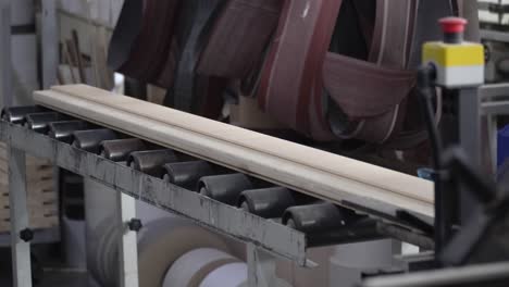Slow-motion-close-up-of-wood-on-a-conveyor-belt-coming-off-a-wood-working-machine