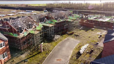 Aerial-view-orbiting-unfinished-waterfront-townhouse-scaffolding-framework-on-property-development-site