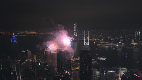 Weitwinkel-Seitlich-Verfolgende-Luftdrohnenaufnahme-Eines-Epischen-Feuerwerks-In-Hong-Kong-City-Bei-Nacht