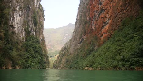 POV-shot-boat-sailing-in-between-mountain-cliff-canyon-in-north-Vietnamese-river