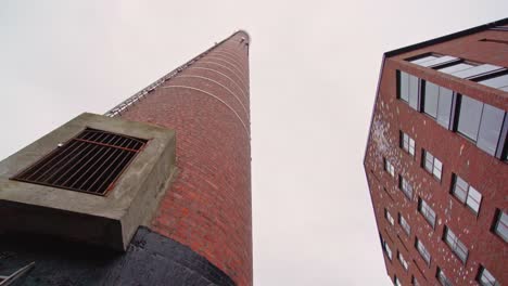 Old-factory-chimney-and-a-modern-apartment-house-against-a-cloudy-sky