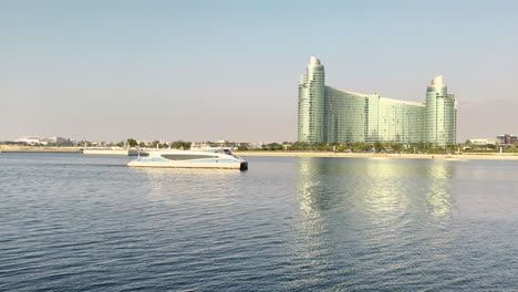 Luxurious-yacht-sailing-on-the-Dubai-creek-in-front-of-a-futuristic-hotel