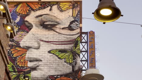 Graffiti-of-a-woman-face-surrounded-by-butterflies-on-a-brick-wall