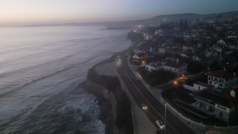 Aerial,-cropped,-drone-shot,-around-Parede-Beach-and-marginal-road,-at-sunset,-on-a-sunny-day,-on-the-coast-of-Estoril,-in-Portugal