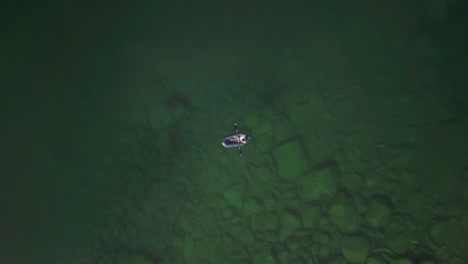 Rising-top-down-aerial-shot-of-a-lone-boater-in-Hatcher-Pass,-Alaska