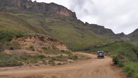 Rugged-Land-Rover-drives-up-rough-gravel-road-of-Sani-Pass,-S-Africa