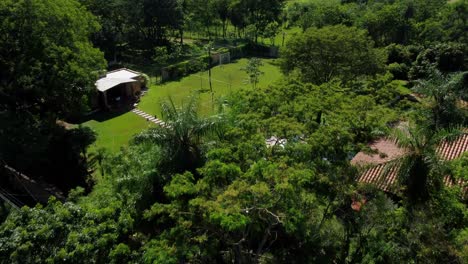 Drone-Flying-Over-Green-Trees-Revealing-Beautiful-Cottage-House-In-Paraguay