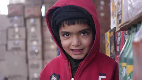 Young-Boy-Wearing-Red-Hoody-Standing-In-Street-Looking-At-Camera-In-Quetta,-Balochistan