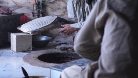Male-Baker-Carefully-Placing-Naan-Bread-Into-Tandoor-Oven-In-Local-Shop-In-Quetta,-Pakistan