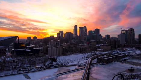 Drone-hyperlapse-of-a-radiant-sunset-behind-Minneapolis-skyscrapers-with-the-Mississippi-River-in-the-foreground