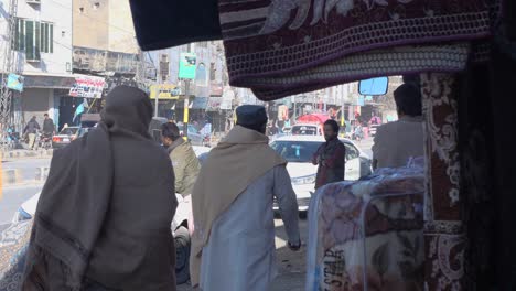 Los-Lugareños-Pasan-Por-La-Acera-Con-El-Tráfico-Pasando-En-Quetta,-Baluchistán