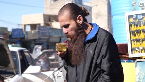 Pakistanischer-Mann-Mit-Langem-Bart,-Der-Auf-Heißes-Getränk-In-Der-Straße-In-Quetta-Bläst