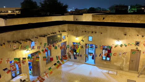 Weiter-Blick-Auf-Die-Altstadt-Vom-Dach-Eines-Traditionell-Gestalteten-Hauses-In-Doha-Katar-Dekoration-Des-Hofes-Durch-Bunte-Fahnen-Warmes-Licht-Sauber-Und-Sicher,-Um-Touristen-Rund-Um-Die-Weltmeisterschaft-Willkommen-Zu-Heißen