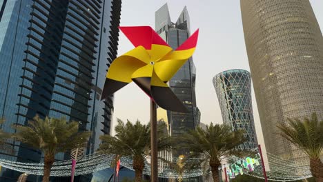 Modern-City-Architecture-glassy-Tower-skyscraper-high-building-Green-Leaf-Palm-Date-Tree-in-sunset-sky-background-and-Belgium-flag-printed-Whirligig-walkway-decoration-design-Doha-Qatar-FIFA-world-cup