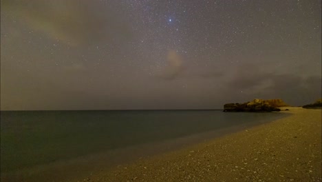 Arabian-gulf-starry-night-sky-wonders-in-a-dark-sand-beach-in-Persian-sea-with-rocky-mountain-scenic-shining-blue-phytoplankton-and-landscape-of-Traditional-boat-sailing-concept-and-marine-lifestyle