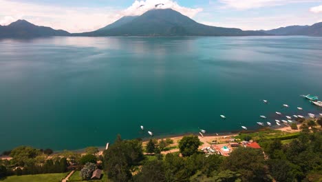 Aerial-Lake-and-Volcano-Pan-Up-from-Coastline---Lake-Atitlan,-Panajachel,-Guatemala