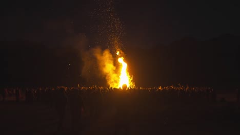 Bonfire-in-Front-of-Large-Crowd-of-People-at-Night,-tribal-gathering,-paganism,-spirituality,-full-moon-rainbow-gathering