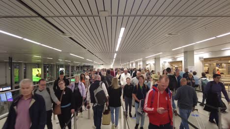 Menge-Von-Passagieren,-Die-In-Der-Warteschlange-Am-Amsterdamer-Flughafen-Schiphol-In-Amsterdam,-Niederlande,-Spazieren-Gehen