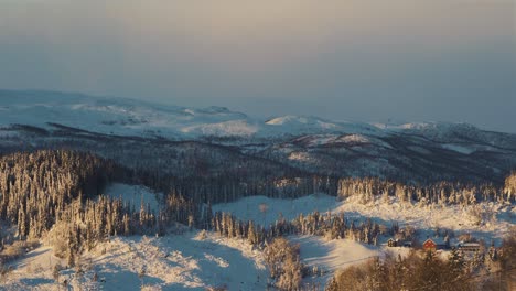 Aerial-wide-shot-of-Beautiful-snowy-landscape-with-icy-forest-trees-during-golden-sunset-in-Norway