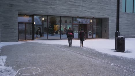 Personas-Que-Se-Dirigen-Hacia-La-Entrada-Del-Museo-Nacional-De-Arte,-Arquitectura-Y-Diseño-En-Oslo,-Noruega,-Con-Nieve-Cayendo
