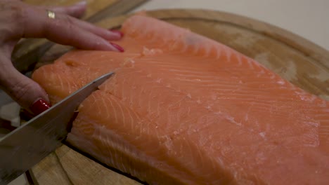 Woman-slicing-salmon-fillet-with-a-kitchen-knife