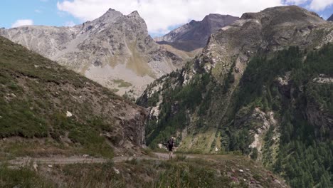 Joven-Excursionista-Caminando-Por-Un-Camino-De-Grava-En-Un-Pintoresco-Valle-En-Los-Hermosos-Alpes-Suizos