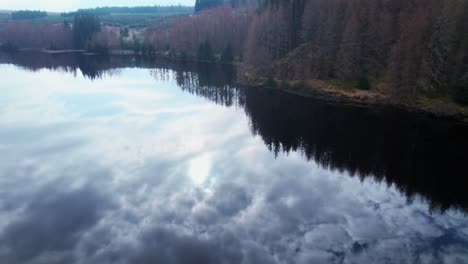 Aerial-drone-flying-above-calm-water-reflecting-clouds,-tilt-up-reveals-landscape,-Loch-Lochy,-Spean-Bridge,-Scotland