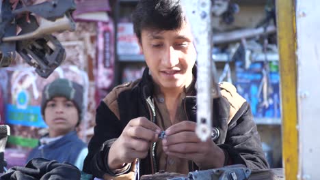 Junger-Mann-Am-Verkaufsstand-Im-Freien-Mit-Hängenden-Autoteilen,-Die-Teil-In-Quetta-Befestigen
