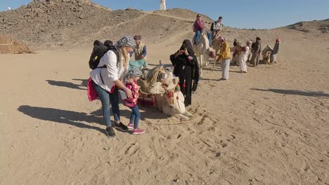 Hurgada,-Egipto-29-De-Diciembre-De-2022:-Los-Camellos-En-El-Desierto-Del-Sahara,-Egipto,-Beduinos-Vestidos-Tradicionales-Montando-Turistas-En-Camellos-A-Través-Del-Desierto-Arenoso