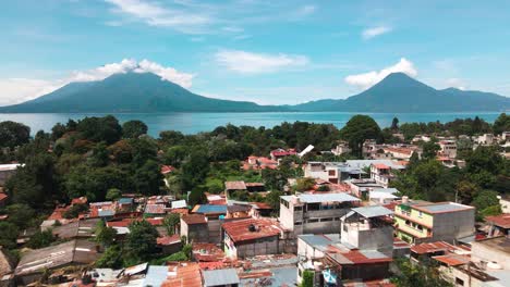 Aerial-Village-Flyover-Toward-Lake-and-Volcanoes---Lake-Atitlan,-Panajachel,-Guatemala