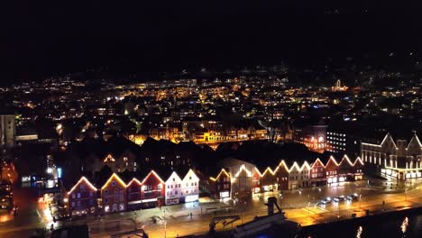 Bryggen-in-Bergen-Norway-illuminated-with-decorative-lights-during-dark-winter-night---Aerial