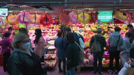 Zahlreiche-Käufer-Sind-An-Einem-Belebten-Obststraßenstand-Zu-Sehen,-Der-Eine-Vielzahl-Von-Früchten-Kauft,-Während-Fußgänger-In-Hongkong-Daran-Vorbeigehen