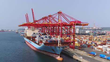 Aerial-drone-of-a-shipping-cargo-ship-being-loaded-with-gantry-cranes-loading-shipping-containers-in-Durban-harbour-4K