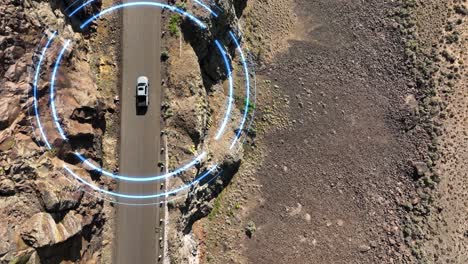 Top-down-drone-shot-of-a-self-driving-car-making-its-way-through-a-steep-desert-cliff-roadway