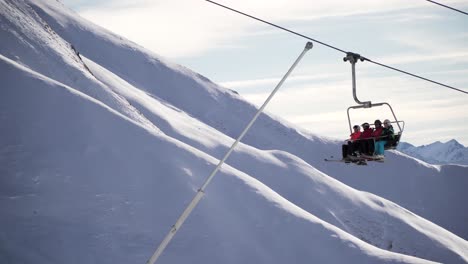 Ski-lift,-chair-lift-with-four-skiers-in-the-cold-alps,-Austria