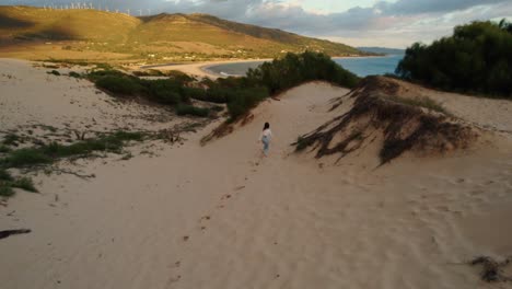 Aerial-view-of-a-woman-running-along-the-beach-at-sunset-in-Tarifa,-Spain
