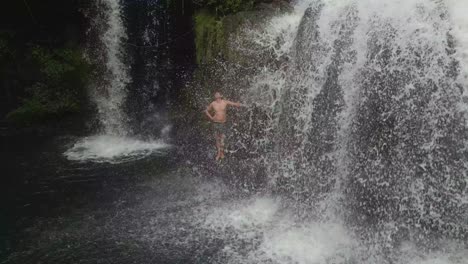 man-showers-under-natural-waterfall