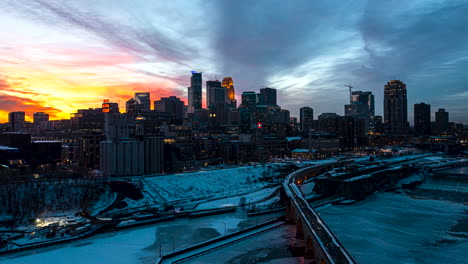 Aerial-hyperlapse-of-the-sun-setting-behind-the-Minneapolis-skyline-with-snow-covering-the-ground